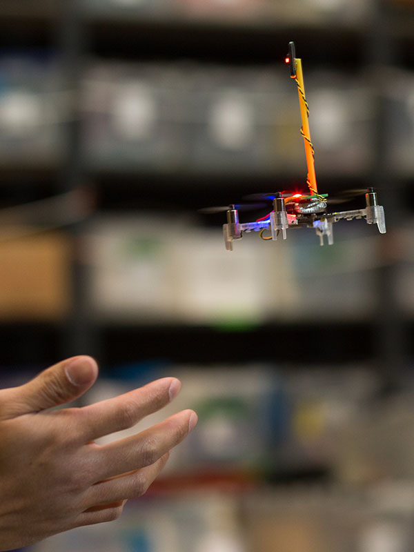 A tiny drone flying by a hand