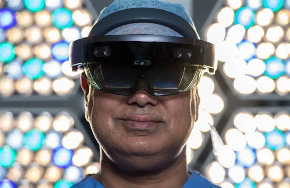 Surgeon Shafi Ahmed poses for a photograph wearing a Microsoft HoloLens headset inside his operating theater at the Royal London Hospital
