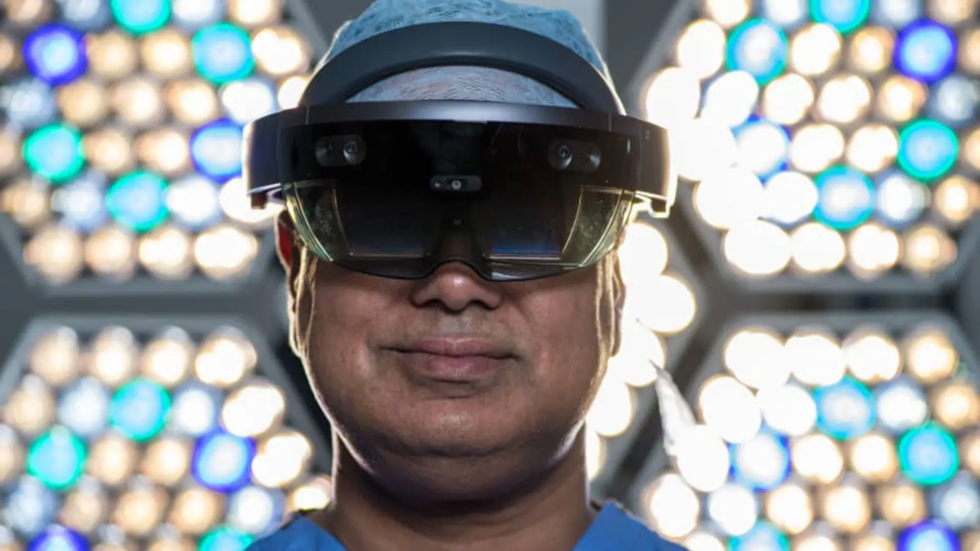 Surgeon Shafi Ahmed poses for a photograph wearing a Microsoft HoloLens headset inside his operating theater at the Royal London Hospital