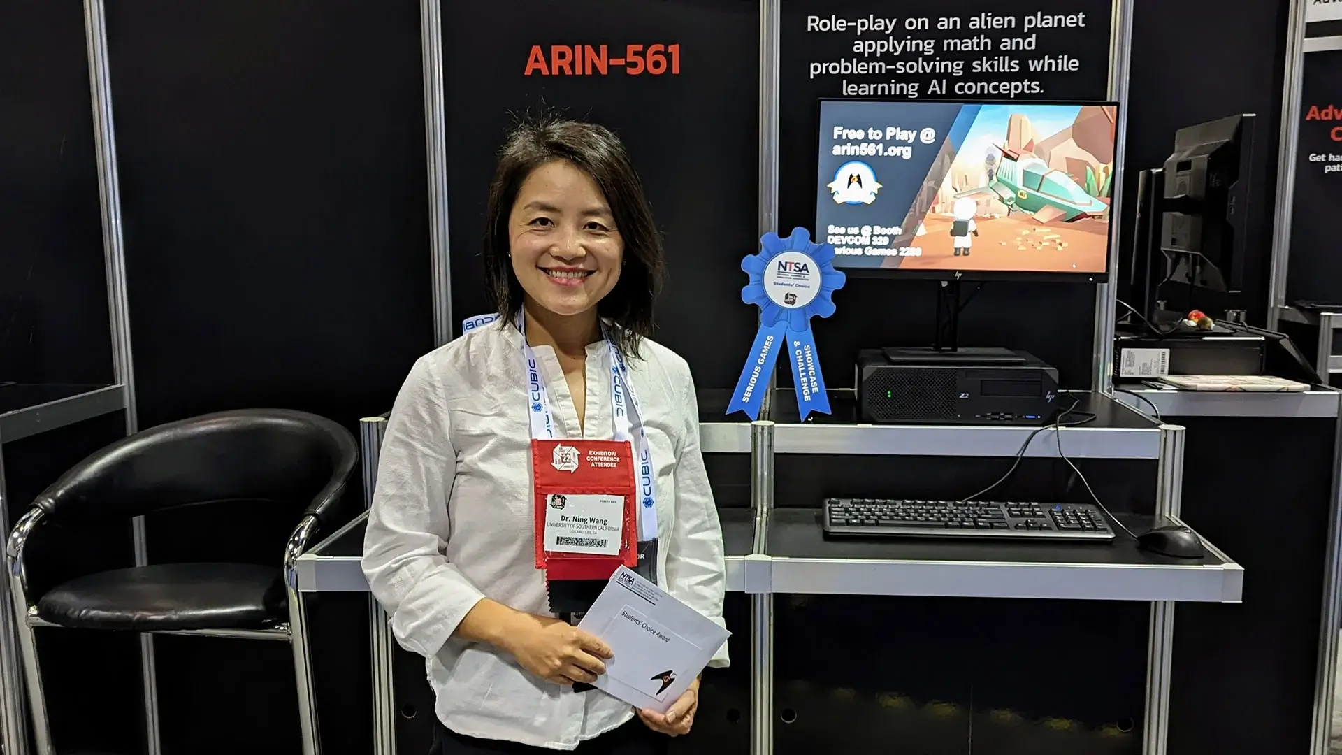 Ning Wang in front of ARIN-561 Game booth at IITSEC 2022
