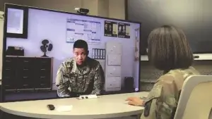 a female solider interacting with a virtual DIVIS character in front of a big television screen