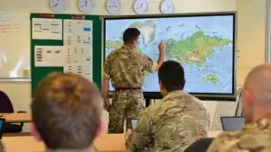 an army men showing the map on a big screen to a group of soldiers