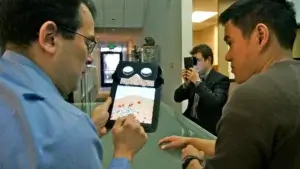 a person showing and explaining the INVRSE reader to the person standing next to him